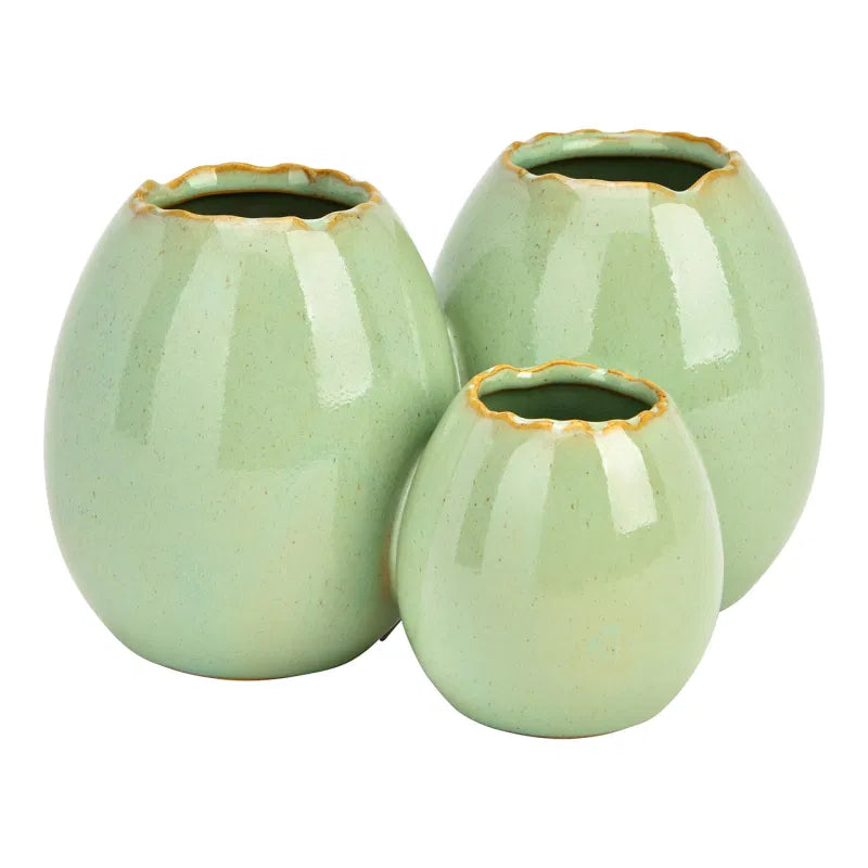 Three light green ceramic vases with gold rims on a white background