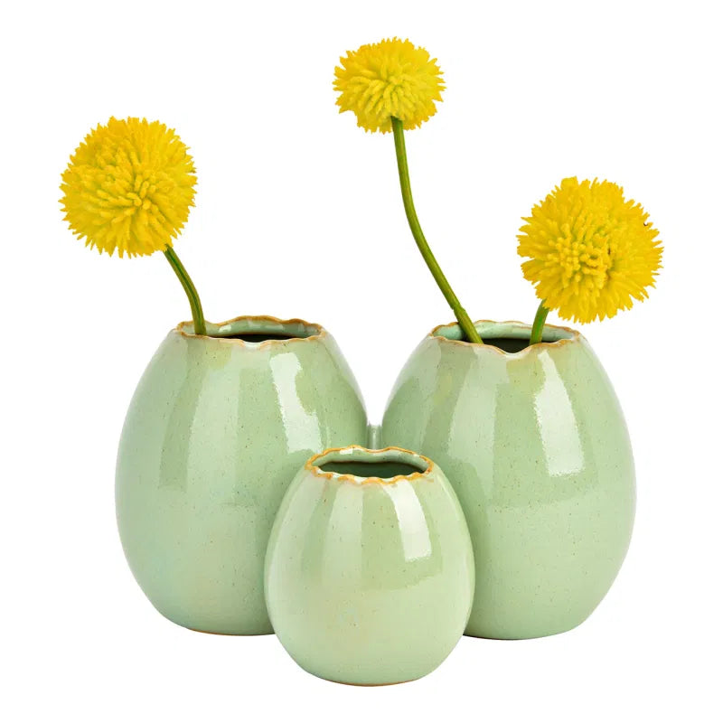Three light green ceramic vases with yellow flowers on a white background