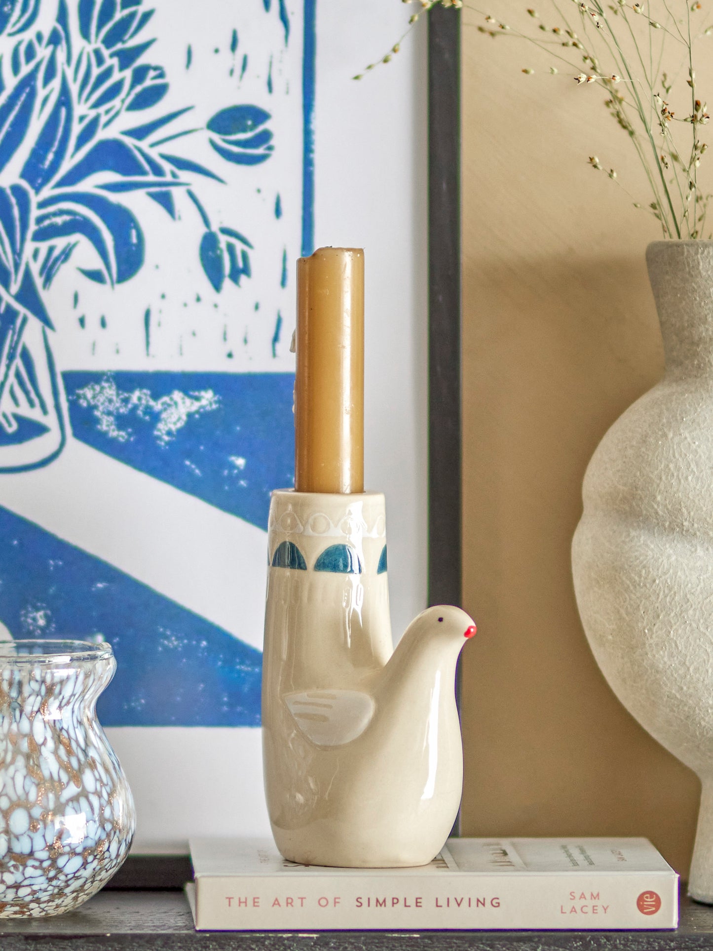 Decorative vases and a book on a shelf with a blue and white patterned wall in the background.