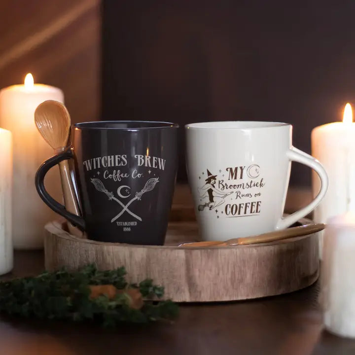 Two mugs with themed designs on a wooden tray with candles in the background