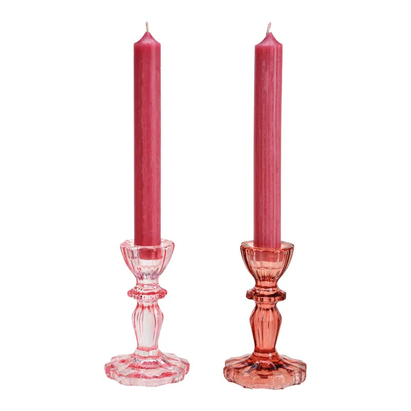 Two pink candles in decorative candlesticks on a white background