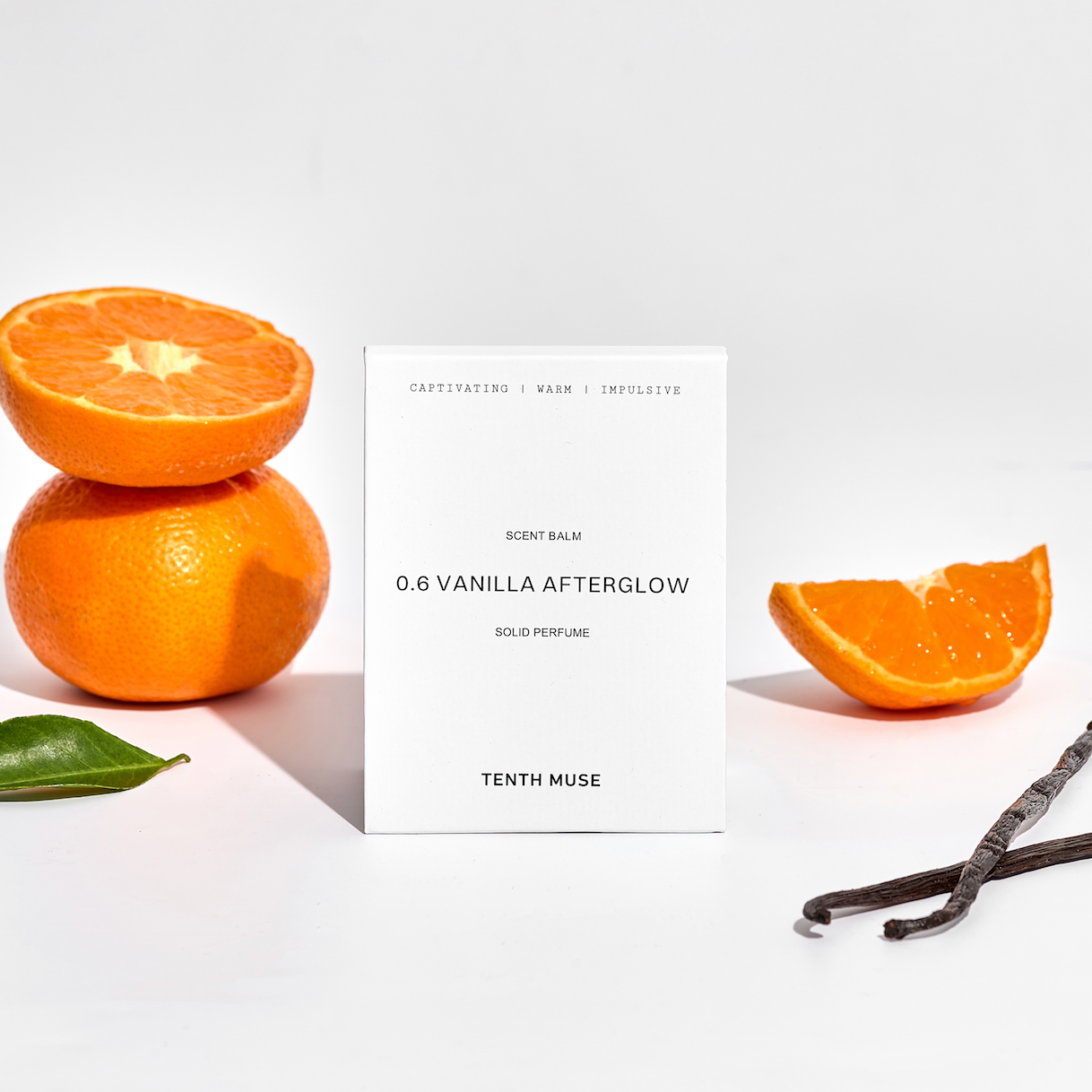 Perfume balm labeled '0.6 Vanilla Afterglow' by Tenth Muse with sliced oranges and vanilla beans on a light background.