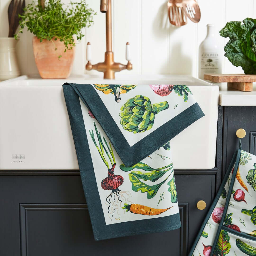 Kitchen towel with vegetable design hanging on a cabinet door