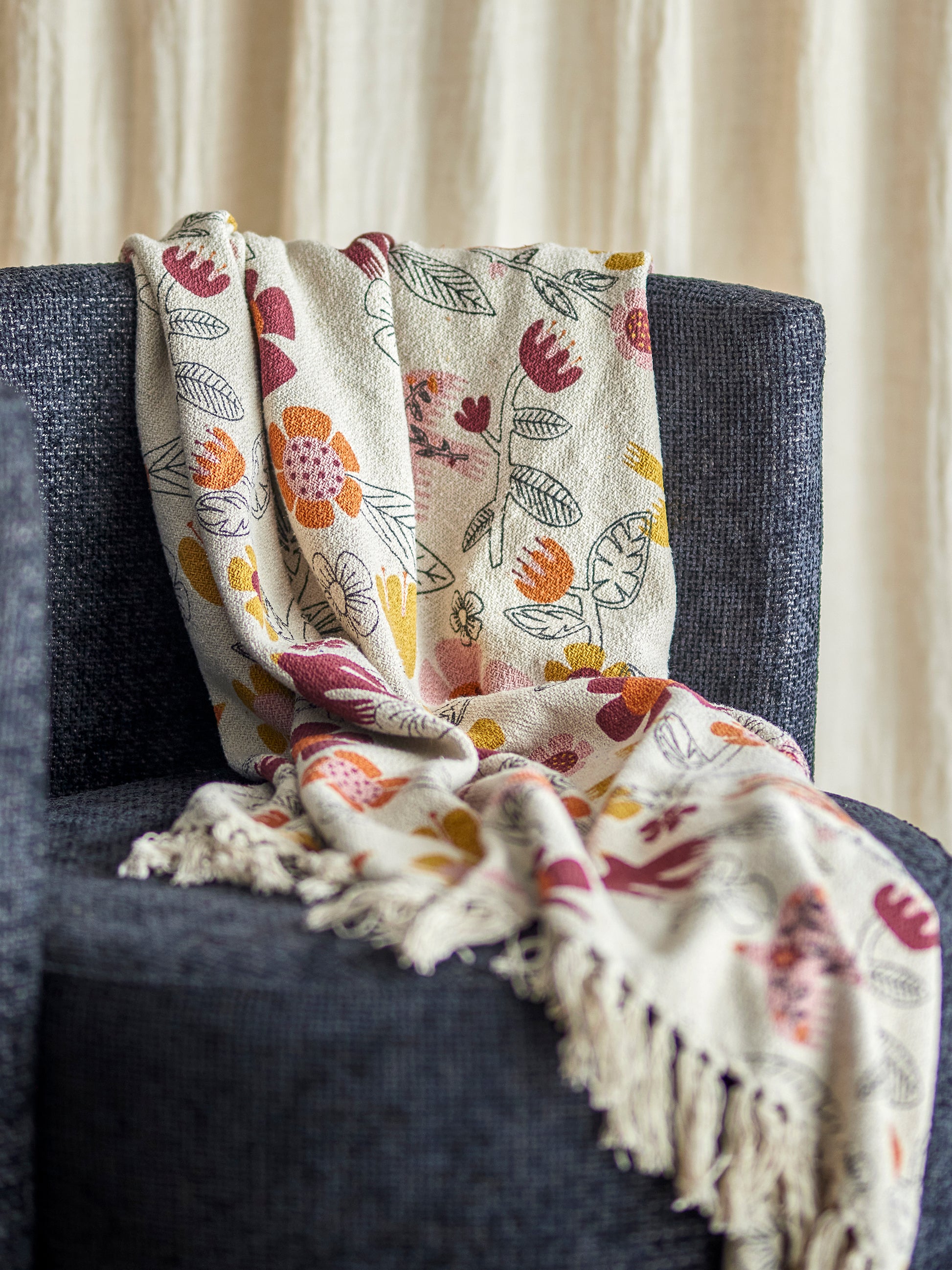 Floral patterned blanket draped over a dark gray chair with a neutral background