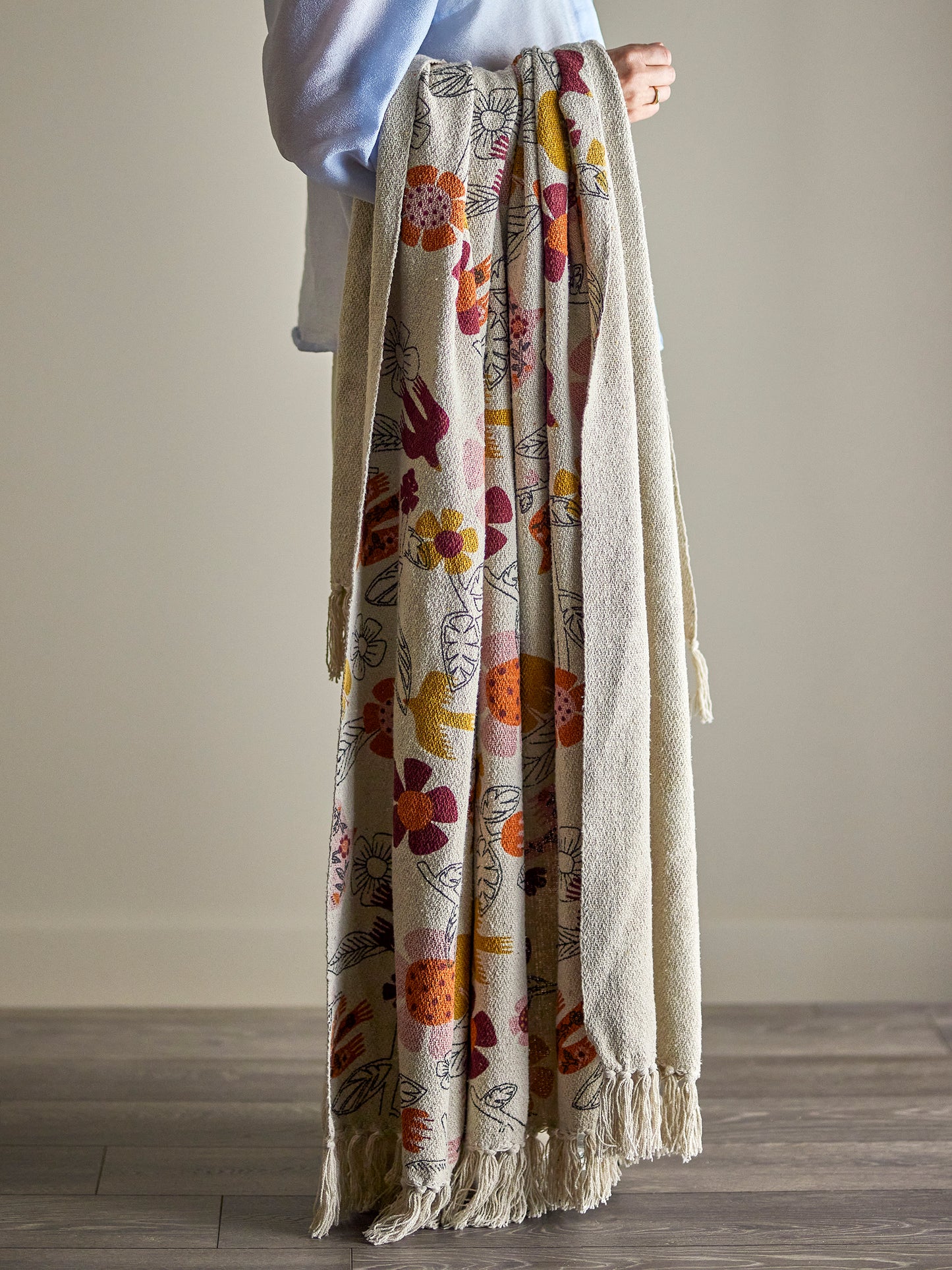 Person holding a floral-patterned blanket with a plain background