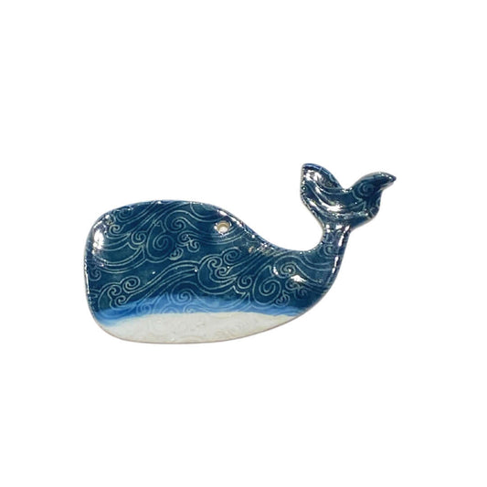 A ceramic hanging decoration in the shape of a whale with blue and white wave patterns.