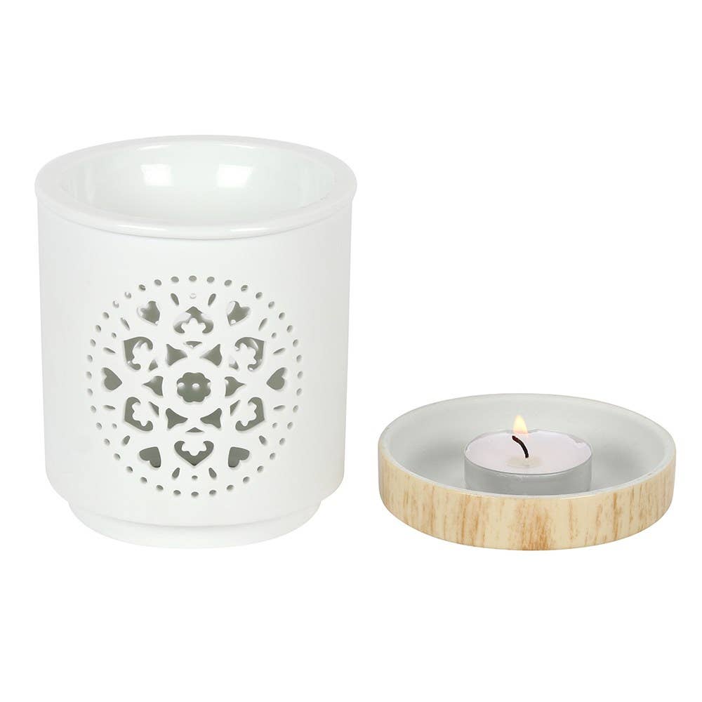 White candle holder with decorative pattern and wooden base with lit candle on a white background