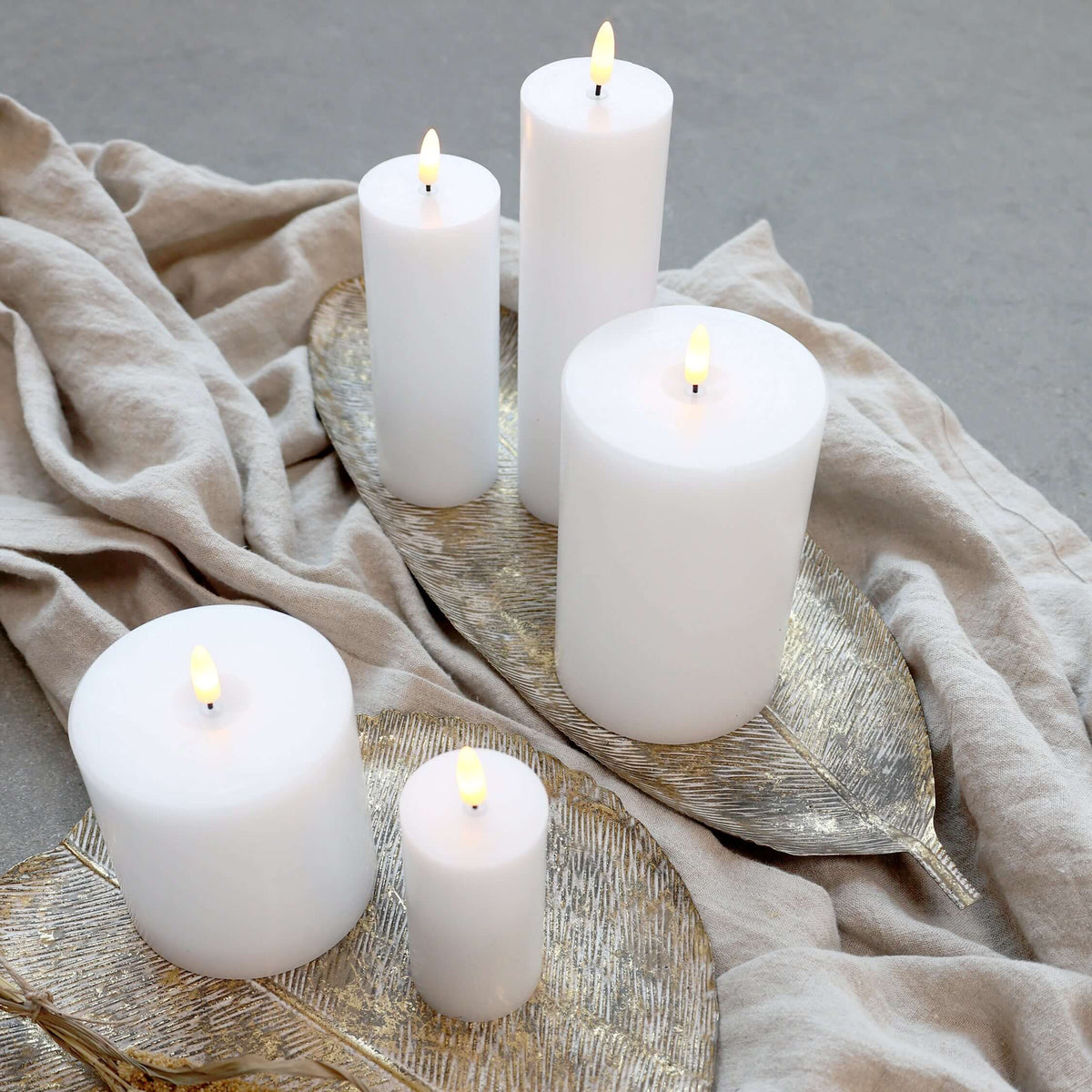 White candles on a decorative tray with a beige cloth background