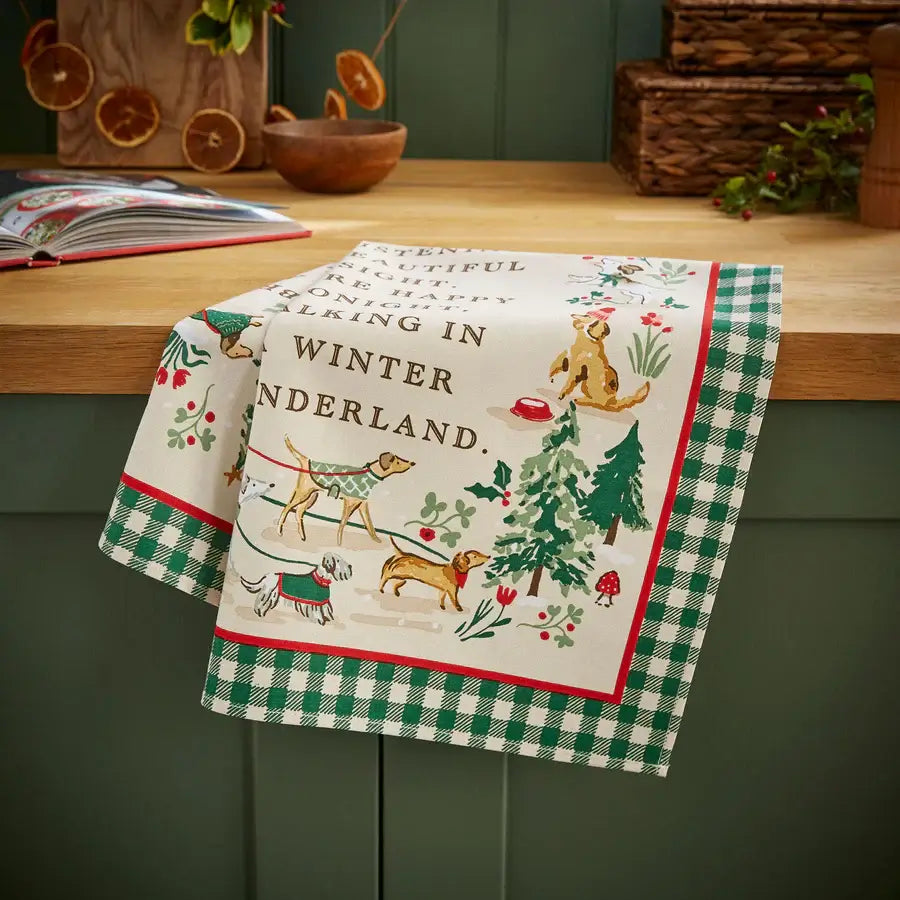 Decorative towel with Christmas-themed design featuring dogs and winter elements on a wooden surface.