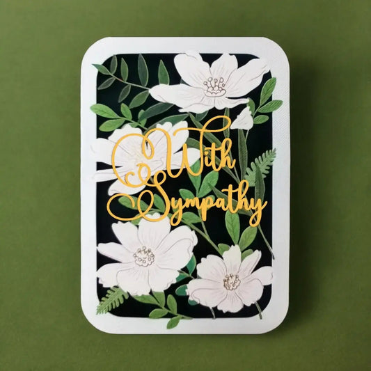 A rectangular sympathy card with rounded corners, featuring white flowers and green leaves on a black background with gold cursive text reading 'With Sympathy', set against an olive green background.