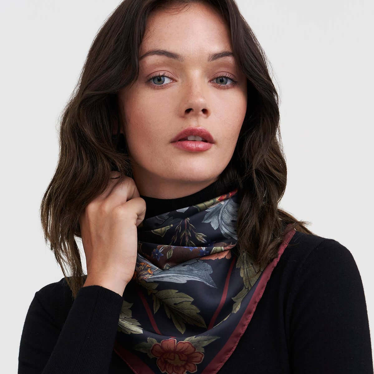Woman wearing a floral scarf on a plain background