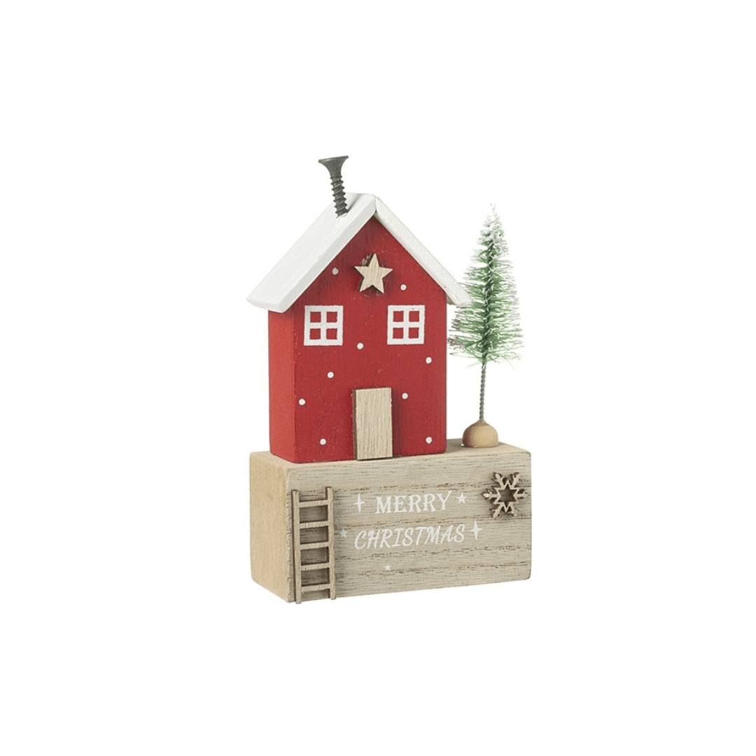 A small decorative Christmas house ornament with a red house on a light wood base, a white roof, a small green tree, and the words “MERRY CHRISTMAS” on the front, shown on a plain white background.