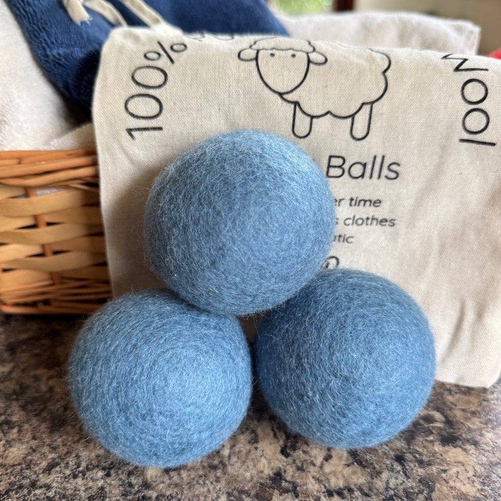 Three blue wool balls with a bag labeled '100% Wool Balls' in the background.