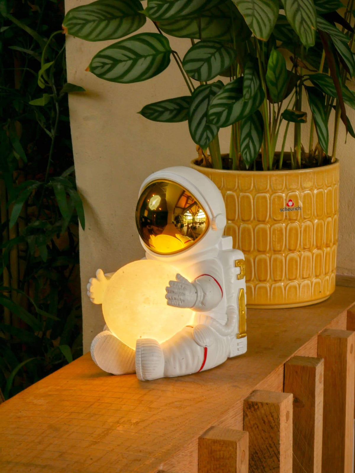 Astronaut bedside light displayed on a shelf among green plants