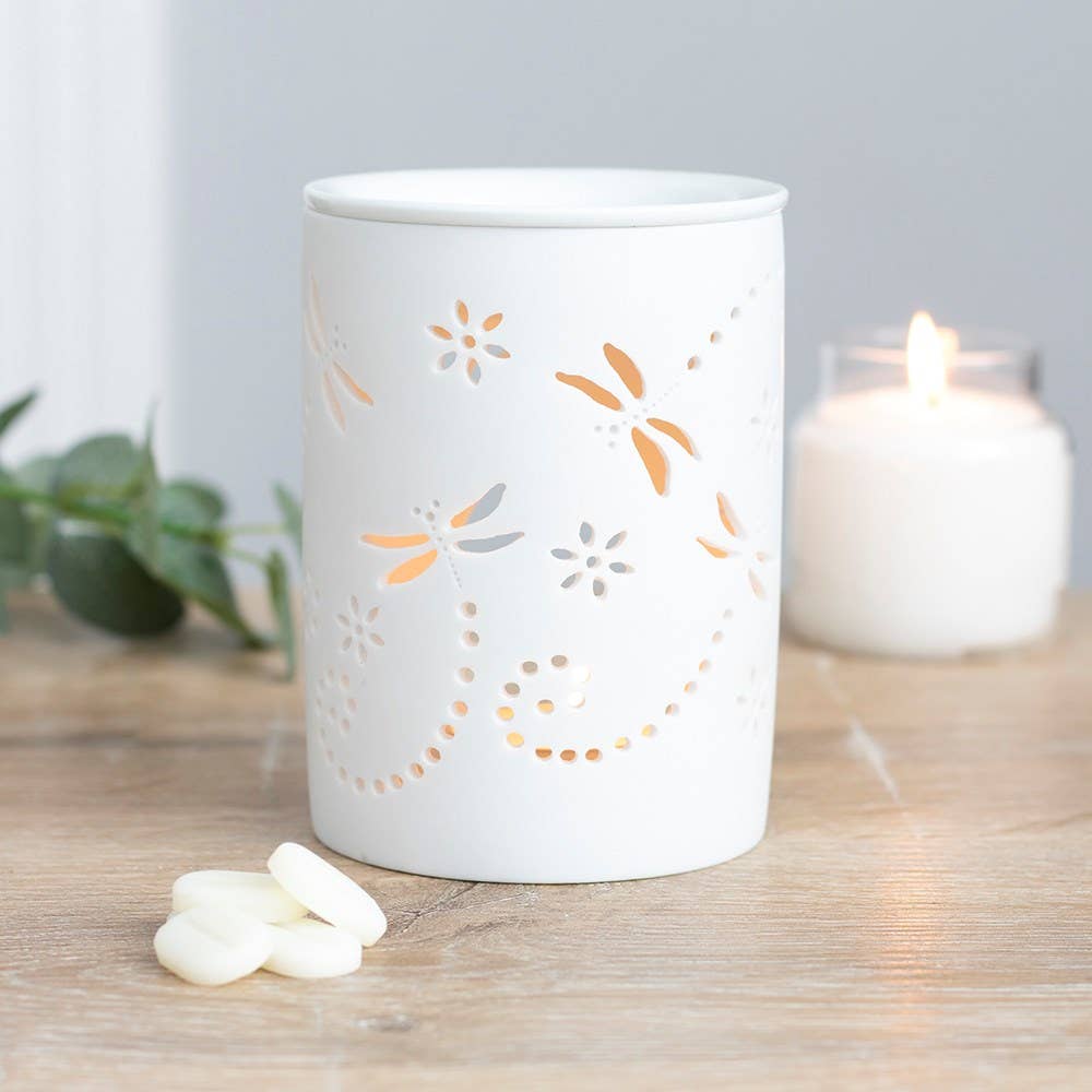 White cut-out dragonfly oil burner and wax warmer styled on a table