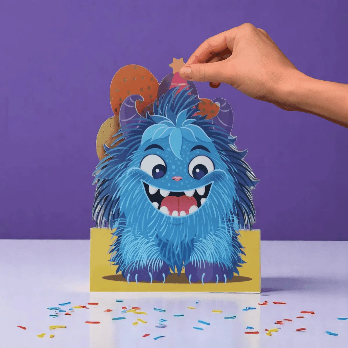 Hand interacting with a blue furry creature card on a purple background