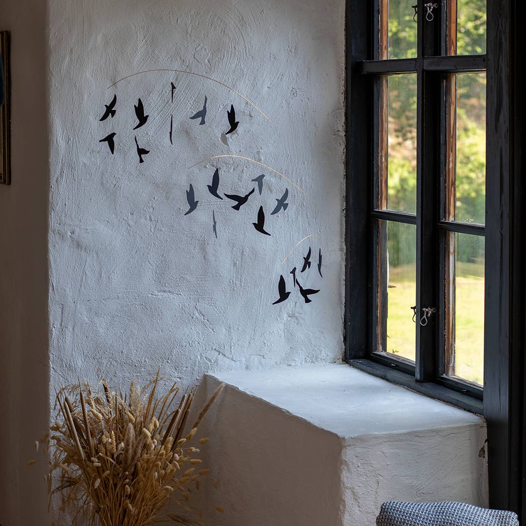 Decorative wall art of birds on a white wall with a window in the background