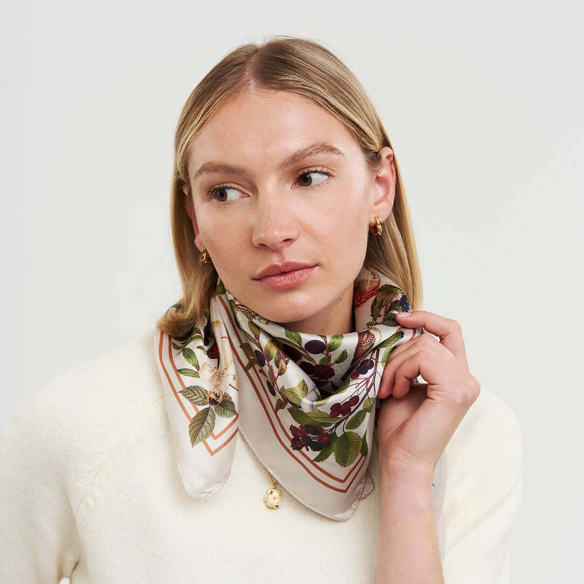 Woman wearing a floral patterned scarf on a plain background
